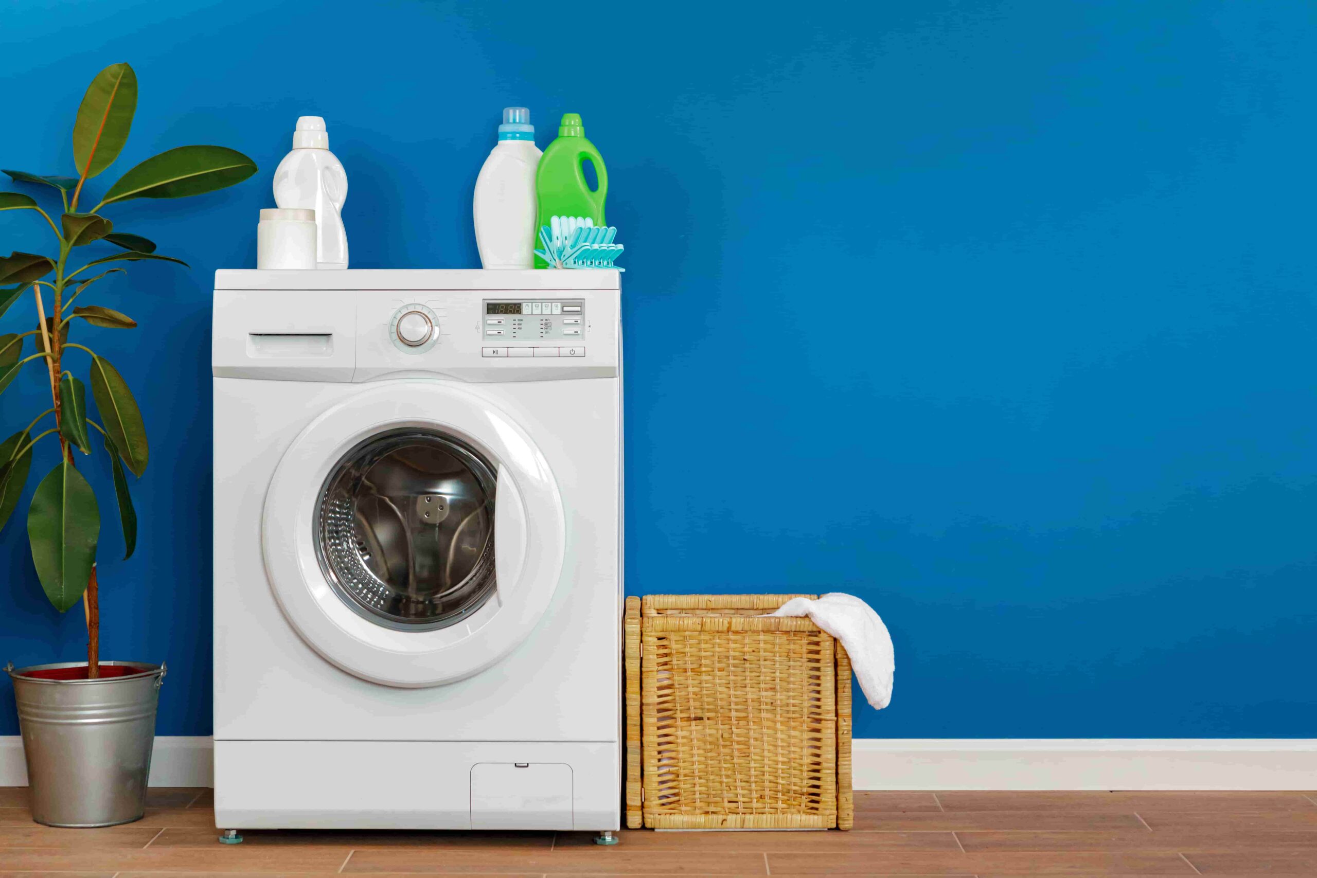 washing-machine-with-laundry-blue-wall-background-close-up-min